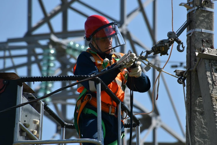 Electrician in safety gear repairing power lines